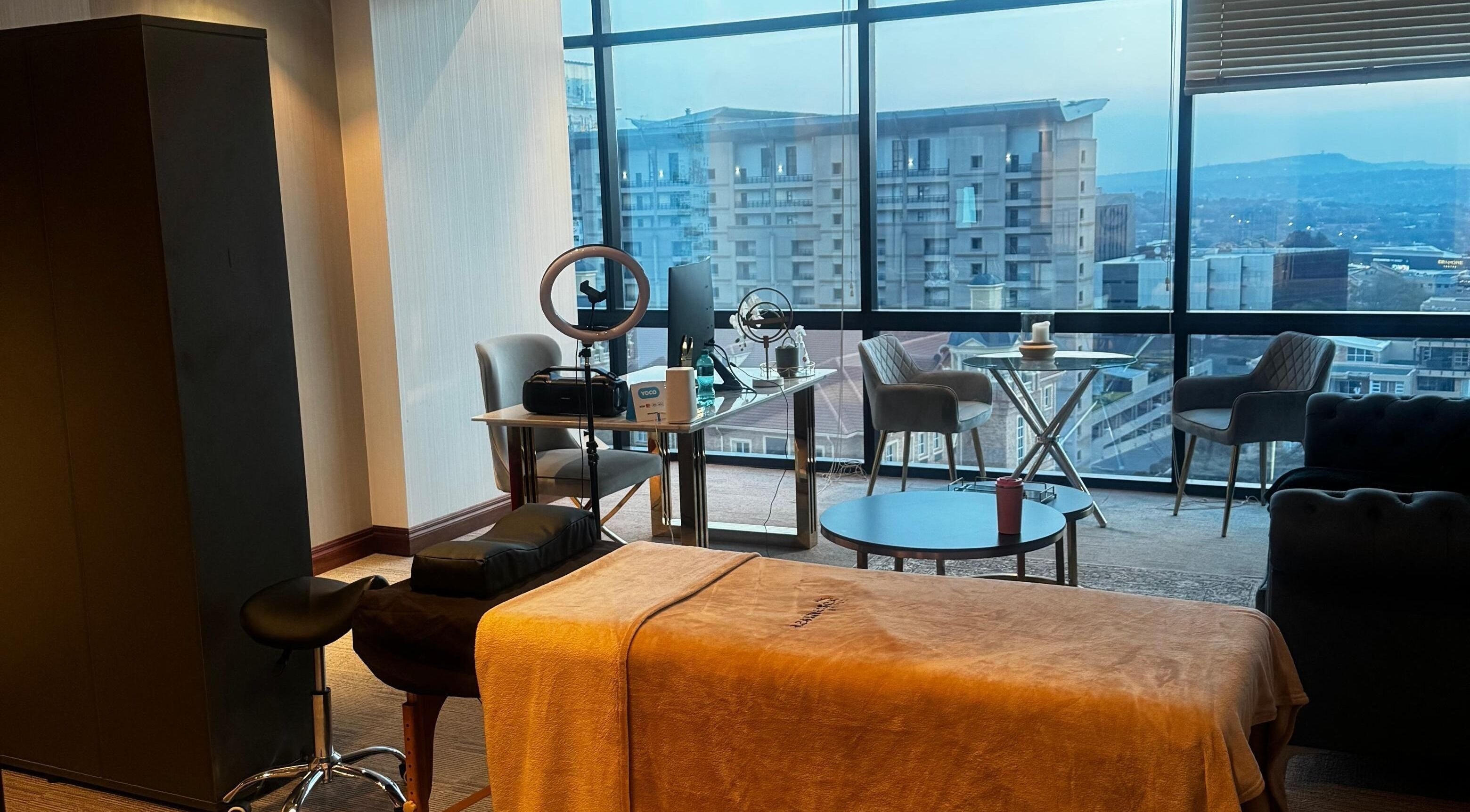 Modern wellness suite at Aestheticsby.Yas in Sandton, Gauteng, ZA with massage bed and city view.