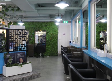 Modern interior of THT - That Hair Tho salon in Dubai, Dubai, AE, featuring sleek chairs and lush greenery.