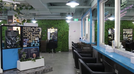 Modern interior of THT - That Hair Tho salon in Dubai, Dubai, AE, featuring sleek chairs and lush greenery.