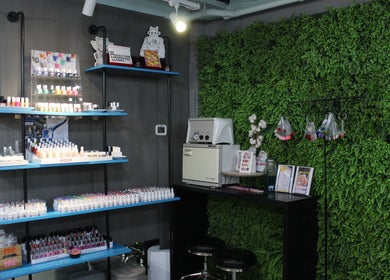 Vibrant nail polish display at THT - That Hair Tho, Dubai, Dubai, AE against a lush green wall.