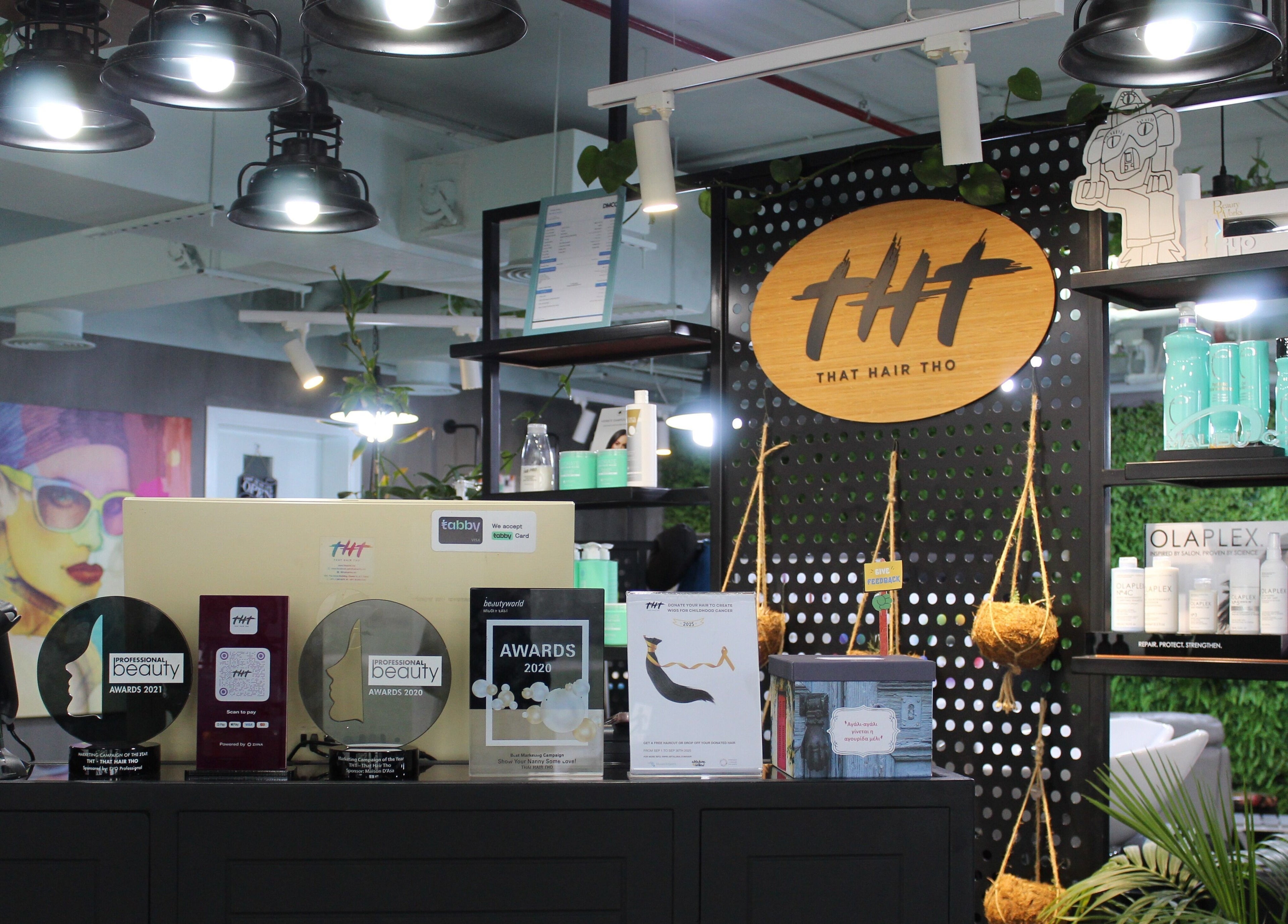 Interior of THT - That Hair Tho in Dubai showcasing awards and products on display shelves.
