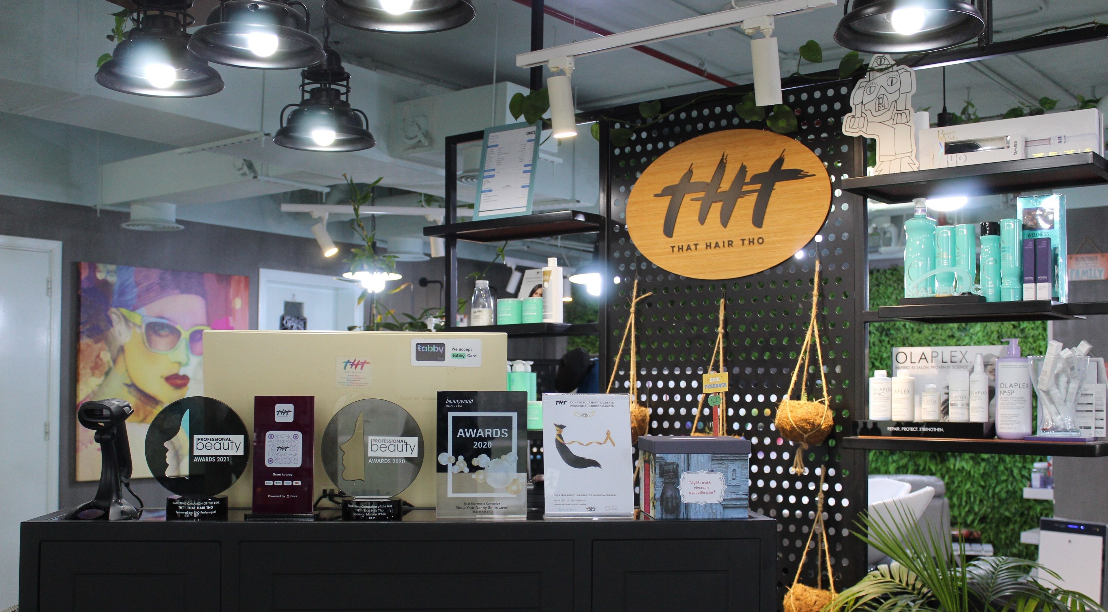 Interior of THT - That Hair Tho in Dubai showcasing awards and products on display shelves.