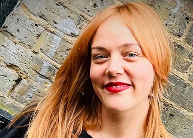 Person with red hair smiling near rustic brick wall at POP West Norwood, London, England, GB.
