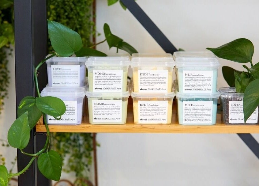Sessions Hairdressing Mcmahons Point featuring eco-friendly hair products on a wooden shelf with plants.