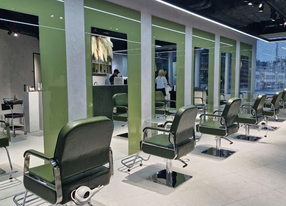 Modern salon interior at LEEKAJA Diamond Plaza in Hồ Chí Minh, featuring chic green chairs and sleek design.