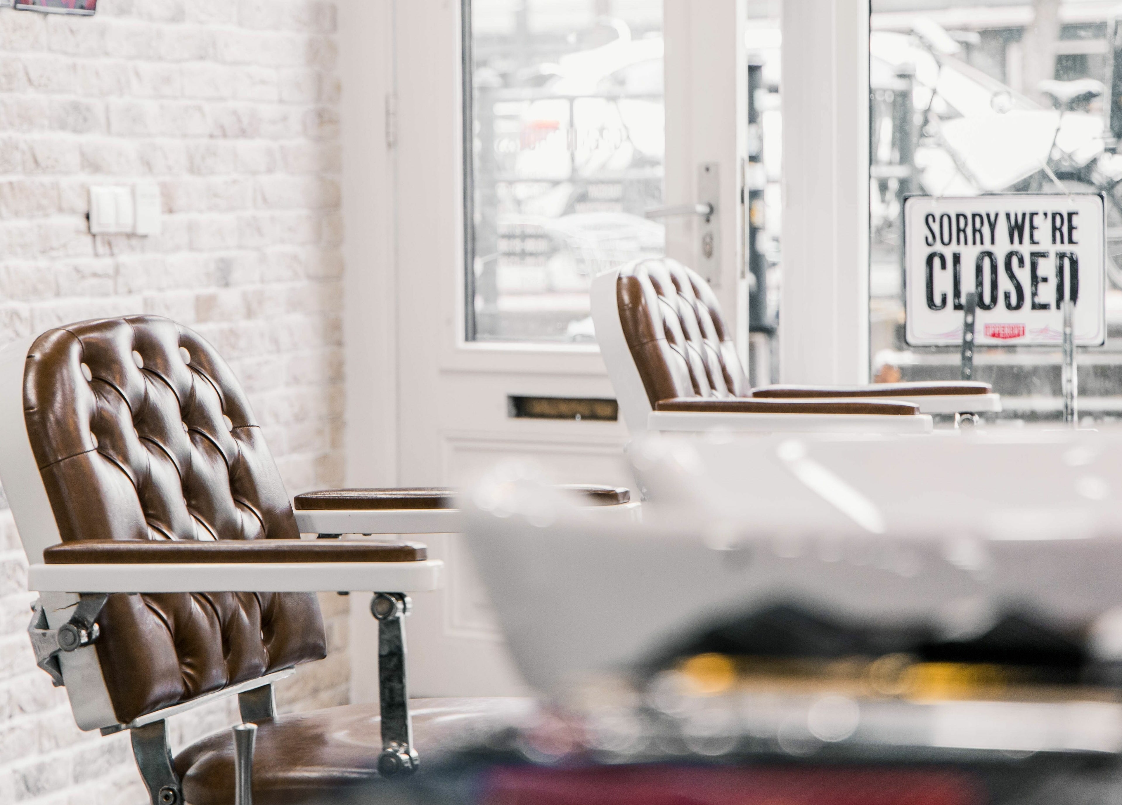 Stylish barbershop chairs at Strak Strak - Barbershop, Rotterdam, South Holland, NL, with closed sign.