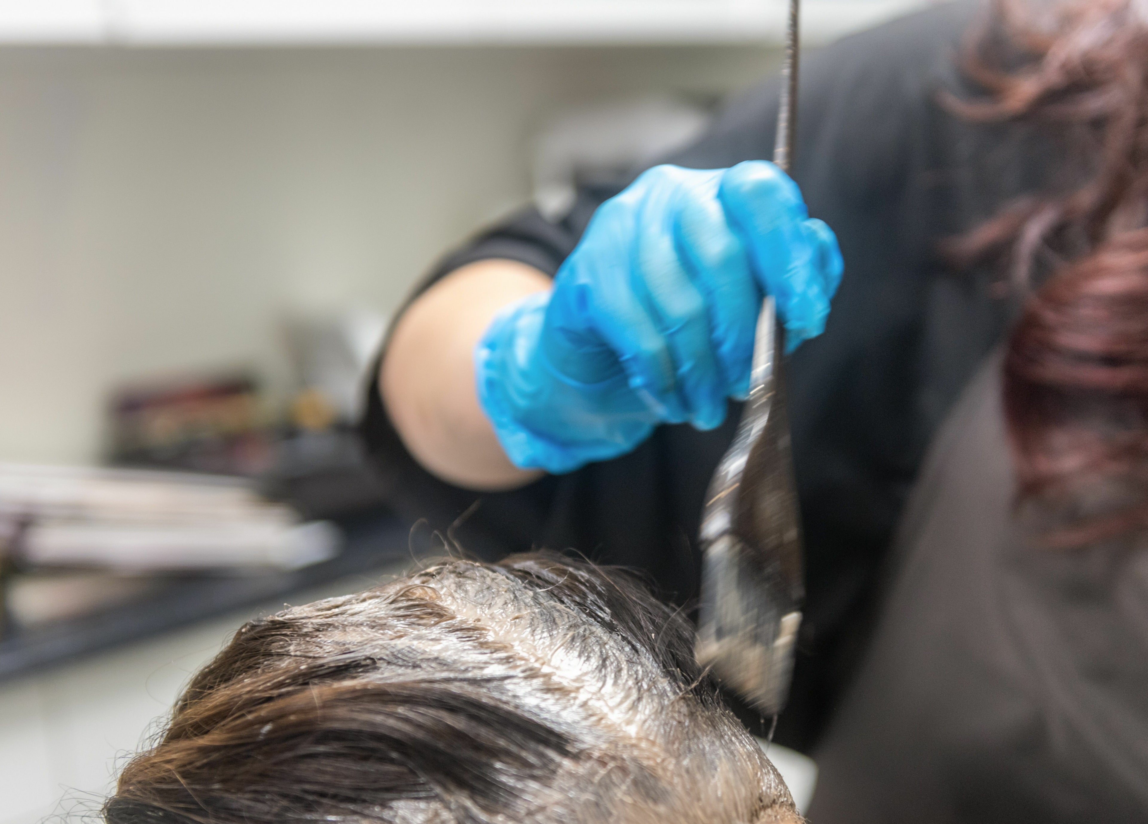 Hair dye application at Balayage Studio, New York, New York, US. Stylist uses brush to apply color.