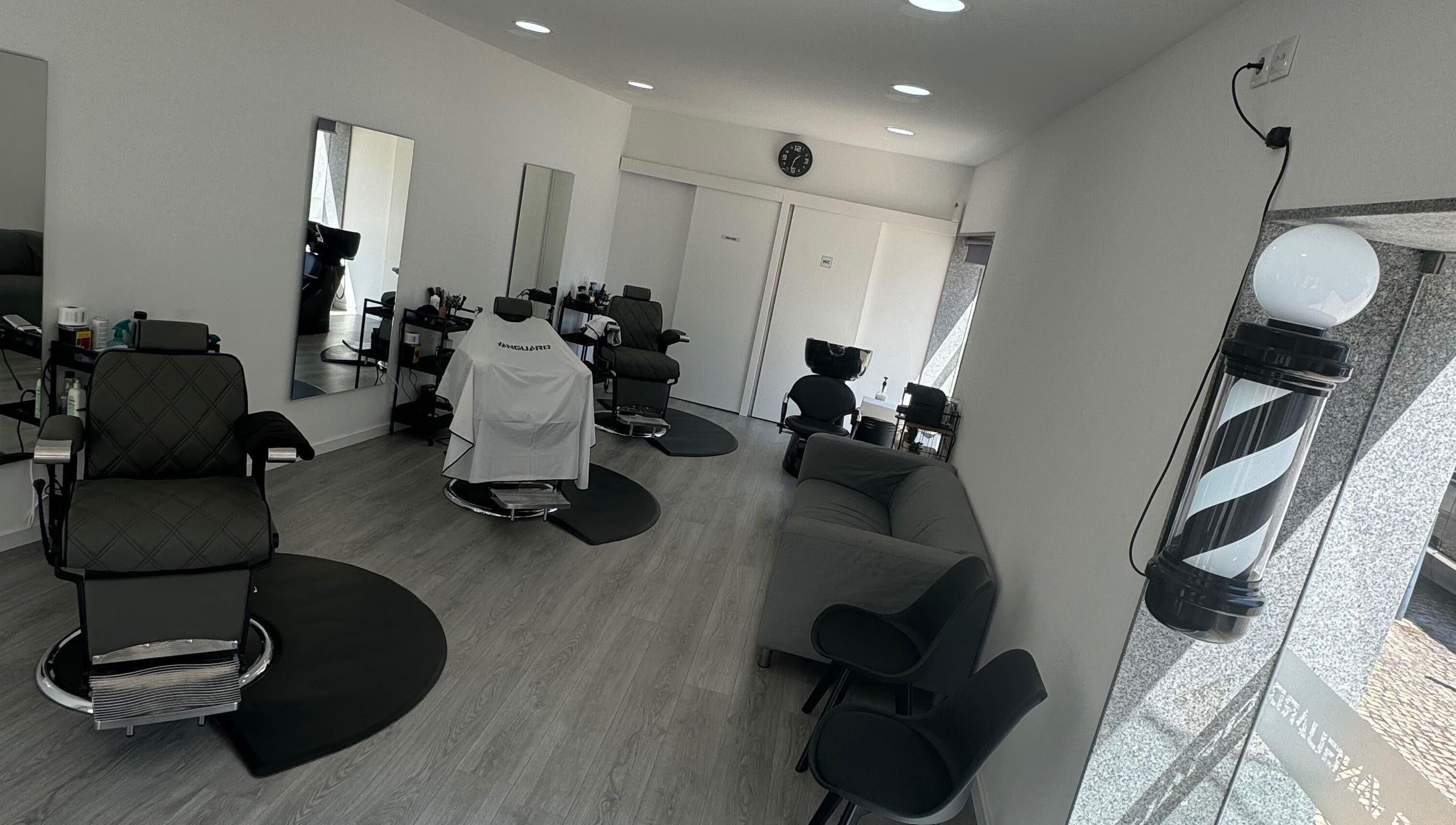 Interior moderno da Araujo Barbershop em Ílhavo, Aveiro, PT, com cadeiras de barbeiro e decoração elegante.