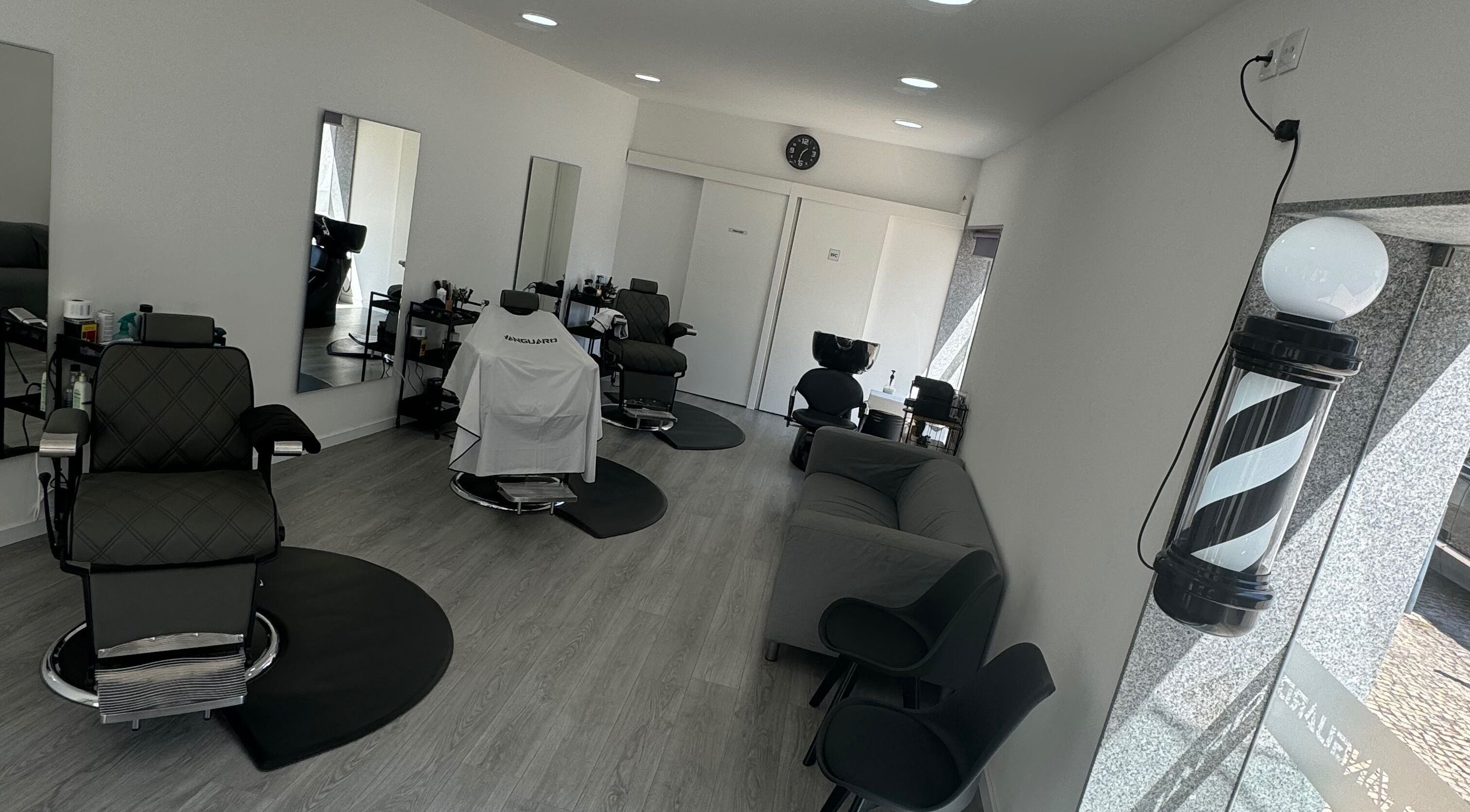 Interior moderno da Araujo Barbershop em Ílhavo, Aveiro, PT, com cadeiras de barbeiro e decoração elegante.