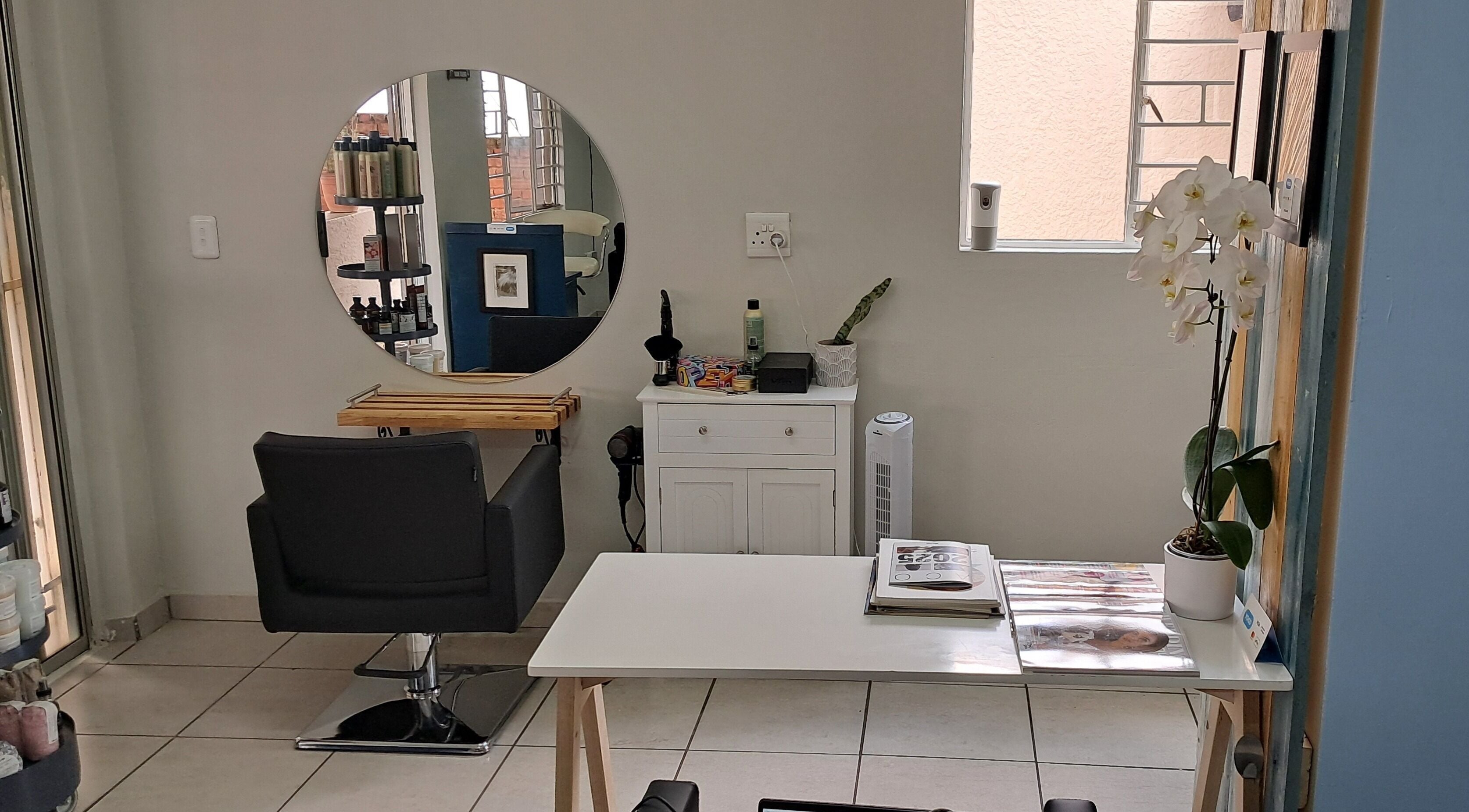 Stylish hair station at Hairon116 in Roodepoort, Gauteng, ZA with mirror, chair, and beauty products.