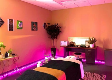 A serene massage room at Ashley's Healing Massage, Fort Lauderdale, Florida, US, with ambient pink lighting.