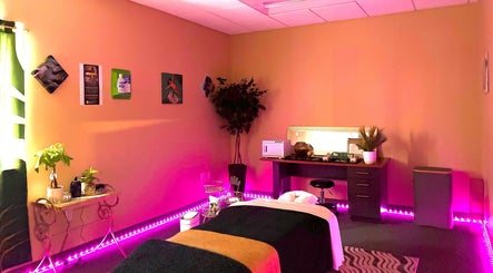 A serene massage room at Ashley's Healing Massage, Fort Lauderdale, Florida, US, with ambient pink lighting.