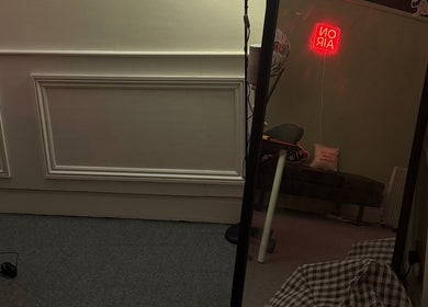 Sleek, modern interior of HT Collective, Dronfield, England, GB with a large mirror reflecting cozy seating.