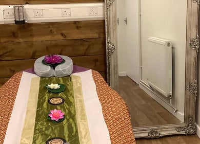 Serene massage room at U Sabai Massage & Spa, Newport, Wales, GB, featuring a decorated table and elegant mirror.