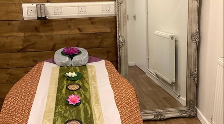 Serene massage room at U Sabai Massage & Spa, Newport, Wales, GB, featuring a decorated table and elegant mirror.