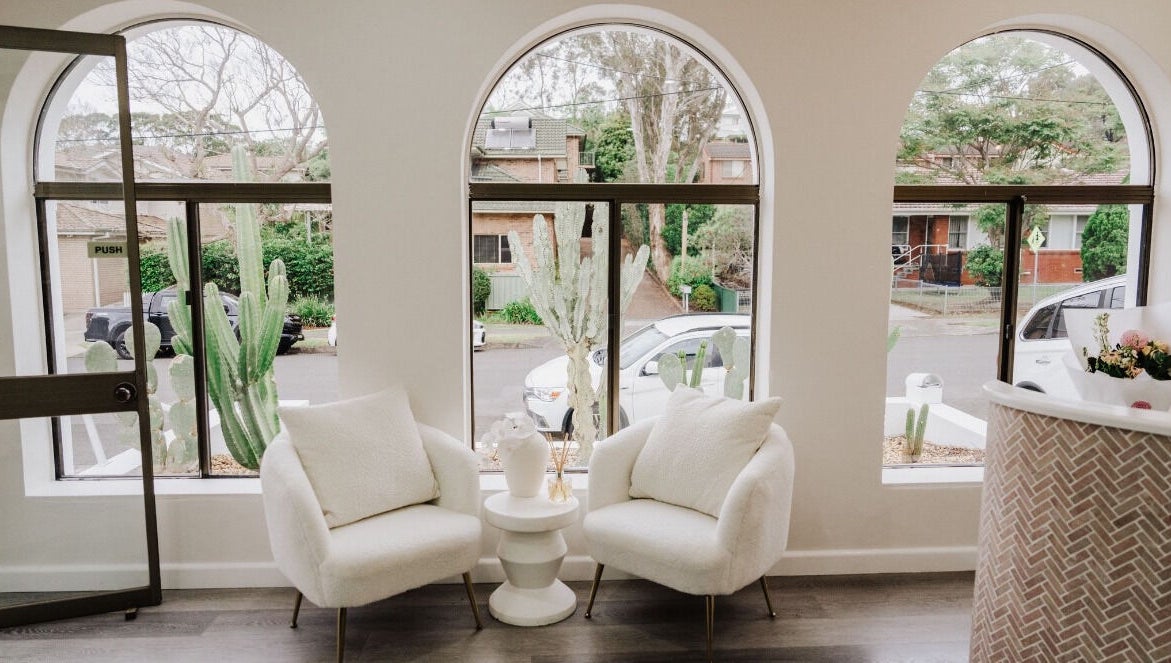 Elegant seating area in KEIRAVILLE THE SALON, Keiraville, New South Wales, AU with large arched windows and greenery.