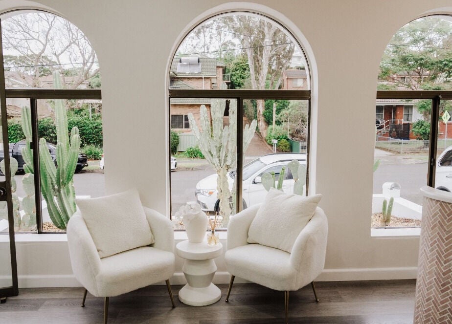 Elegant seating area in KEIRAVILLE THE SALON, Keiraville, New South Wales, AU with large arched windows and greenery.