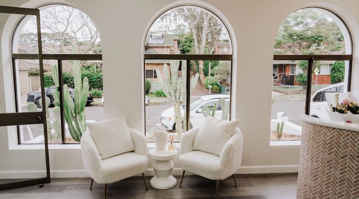Elegant seating area in KEIRAVILLE THE SALON, Keiraville, New South Wales, AU with large arched windows and greenery.