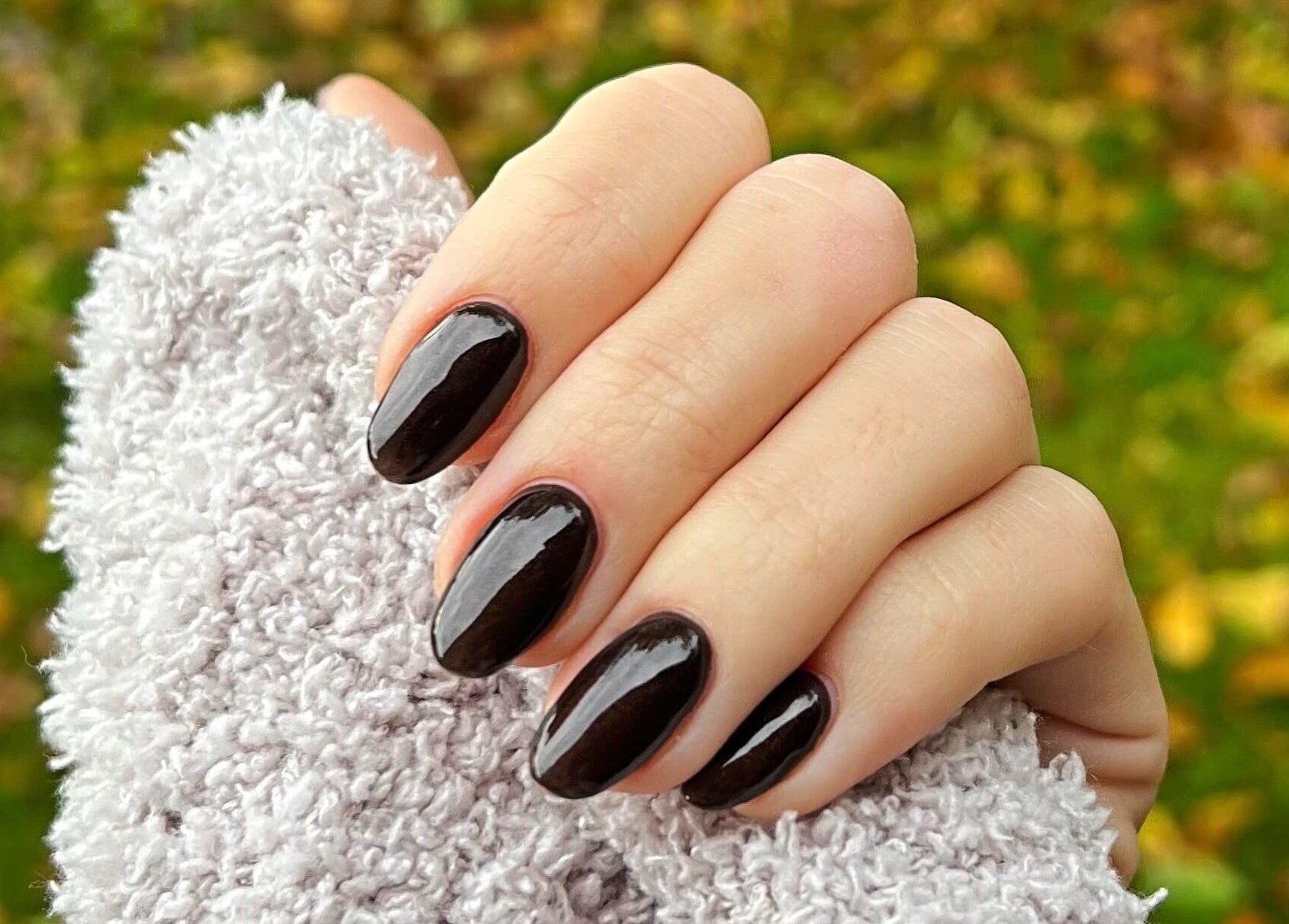 Elegant ebony nails with a glossy finish at Megs Manicures, Abbots Leigh, England, GB, set against a cozy knit.