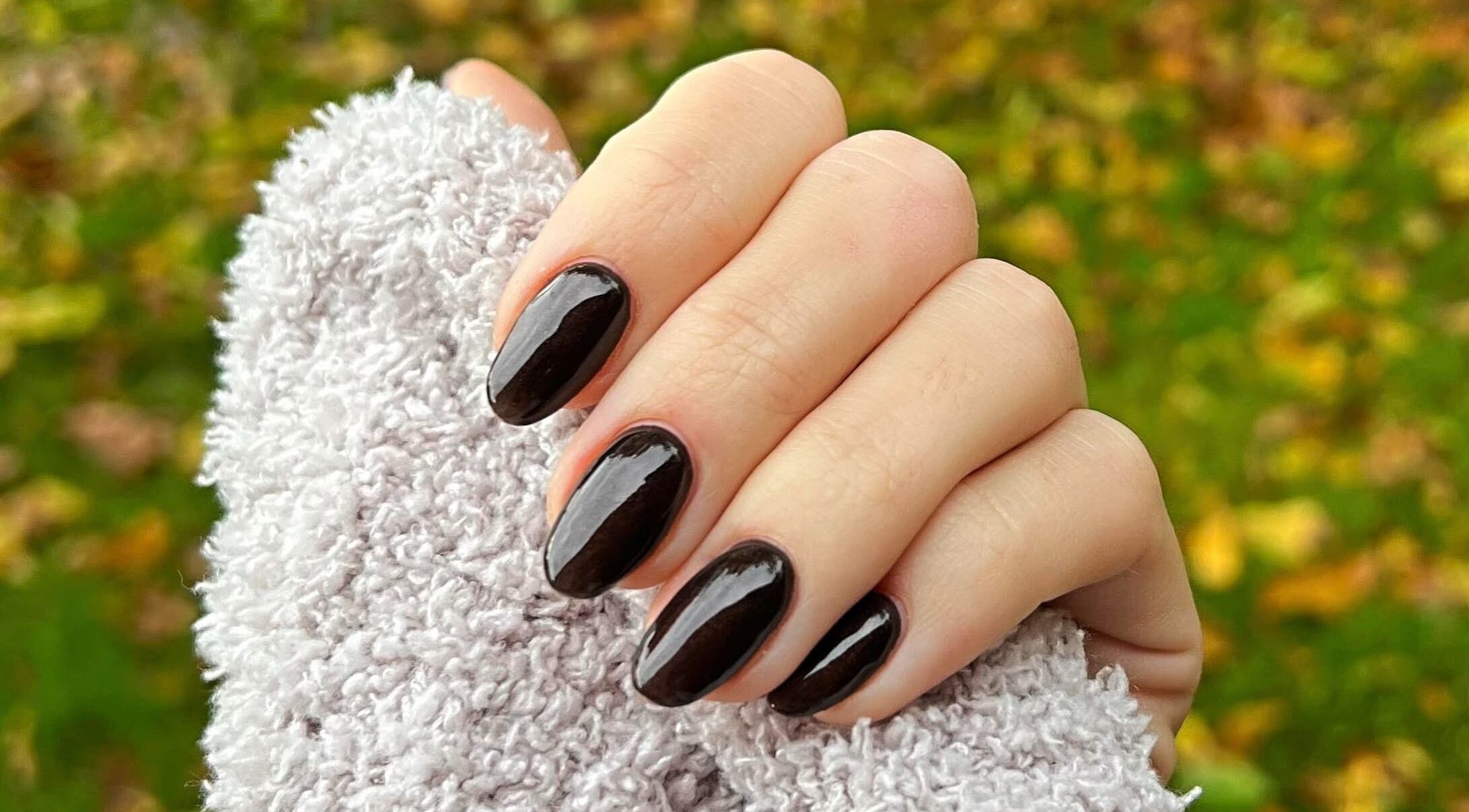 Elegant ebony nails with a glossy finish at Megs Manicures, Abbots Leigh, England, GB, set against a cozy knit.