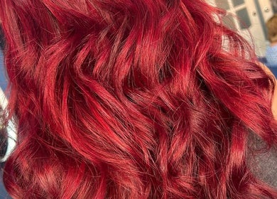 Vibrant red wavy hairstyle at Hair By Jess, Penlle'r-gaer, Cymru, GB salon enhancing stunning hair color.