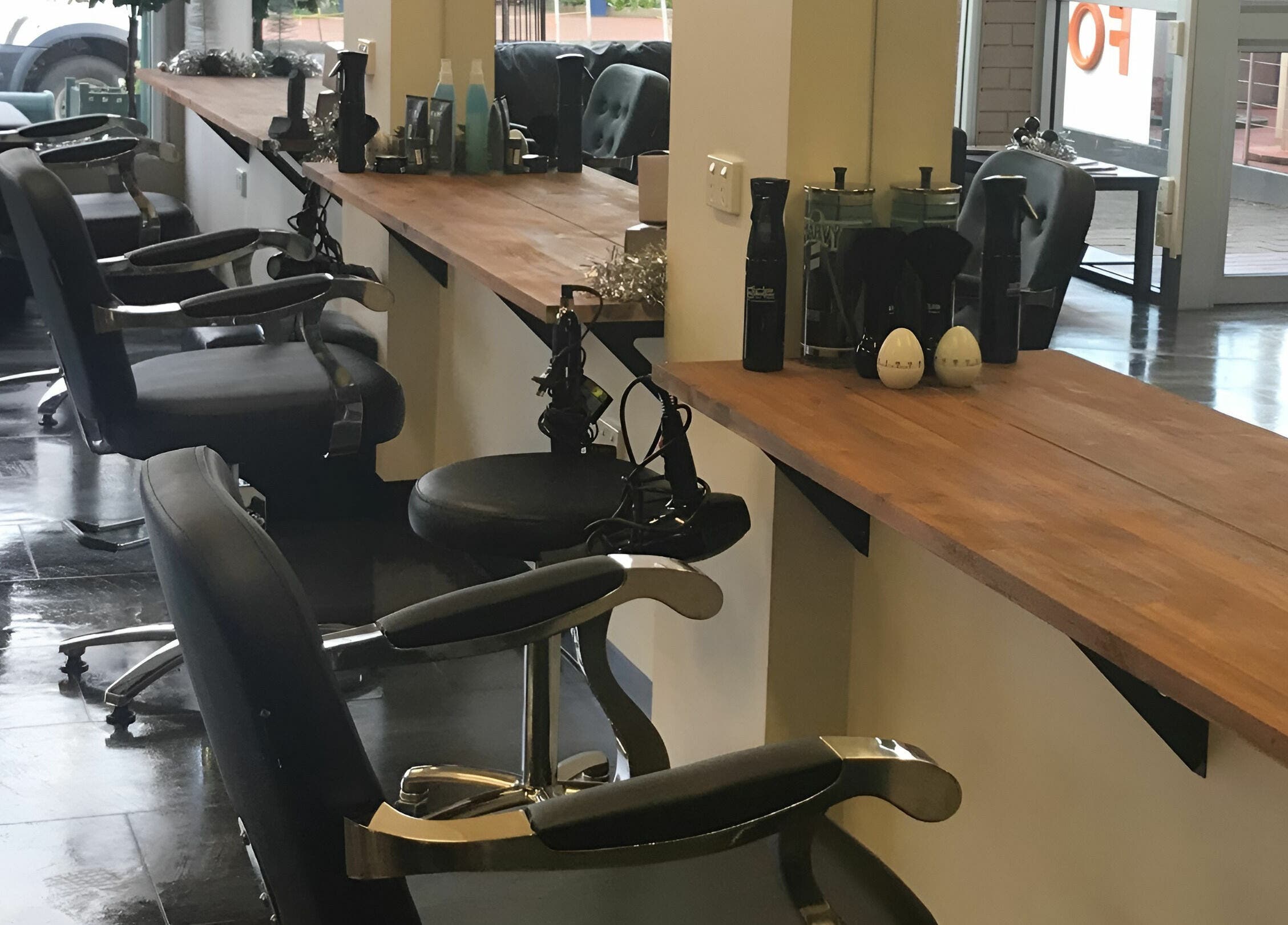 Modern salon booths at Teazed in Scottsdale, Tasmania, AU, featuring sleek black chairs and wooden countertops.