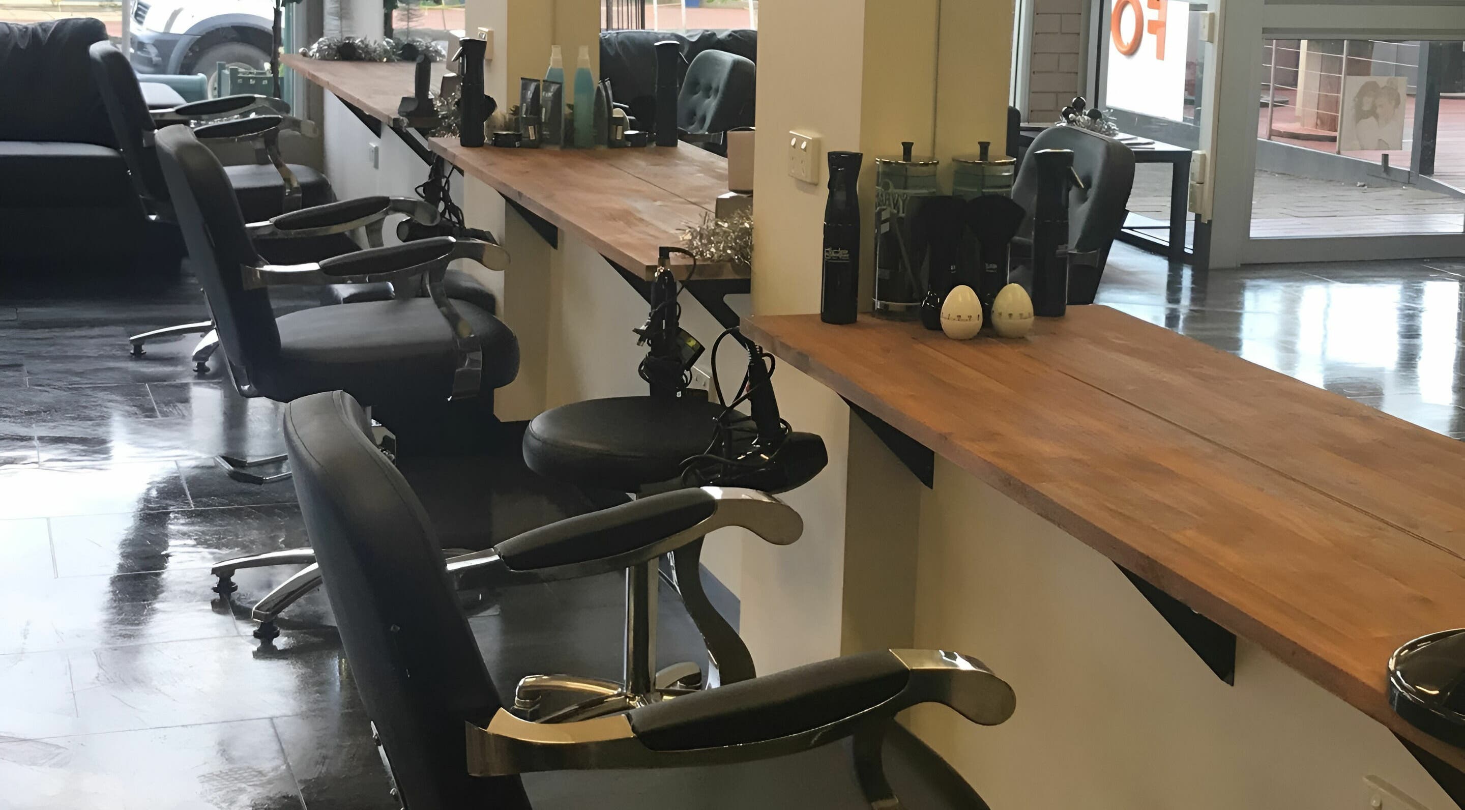 Modern salon booths at Teazed in Scottsdale, Tasmania, AU, featuring sleek black chairs and wooden countertops.