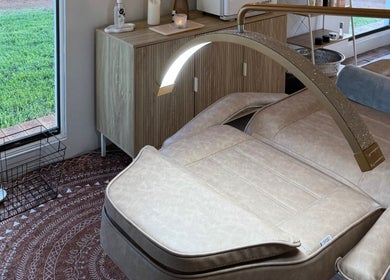 Luxurious spa bed at Tiarne Lauren Beauty in Vasse, Western Australia, AU next to large window with a green view.