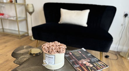 Elgrace Hair Studio lounge in Luton, England, featuring chic decor with a black sofa and rose centerpiece.