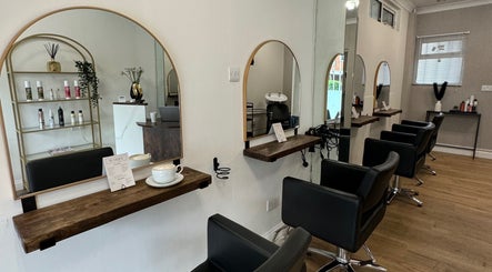 Modern salon interior at Elgrace Hair Studio, Luton, England, GB, featuring stylish black chairs and wooden mirrors.