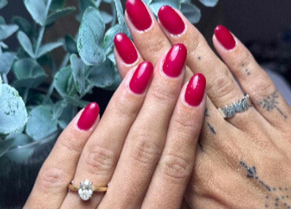 Beautiful red manicured nails at Bantai Beautybar, Chang Wat Surat Thani, featuring lush greenery.