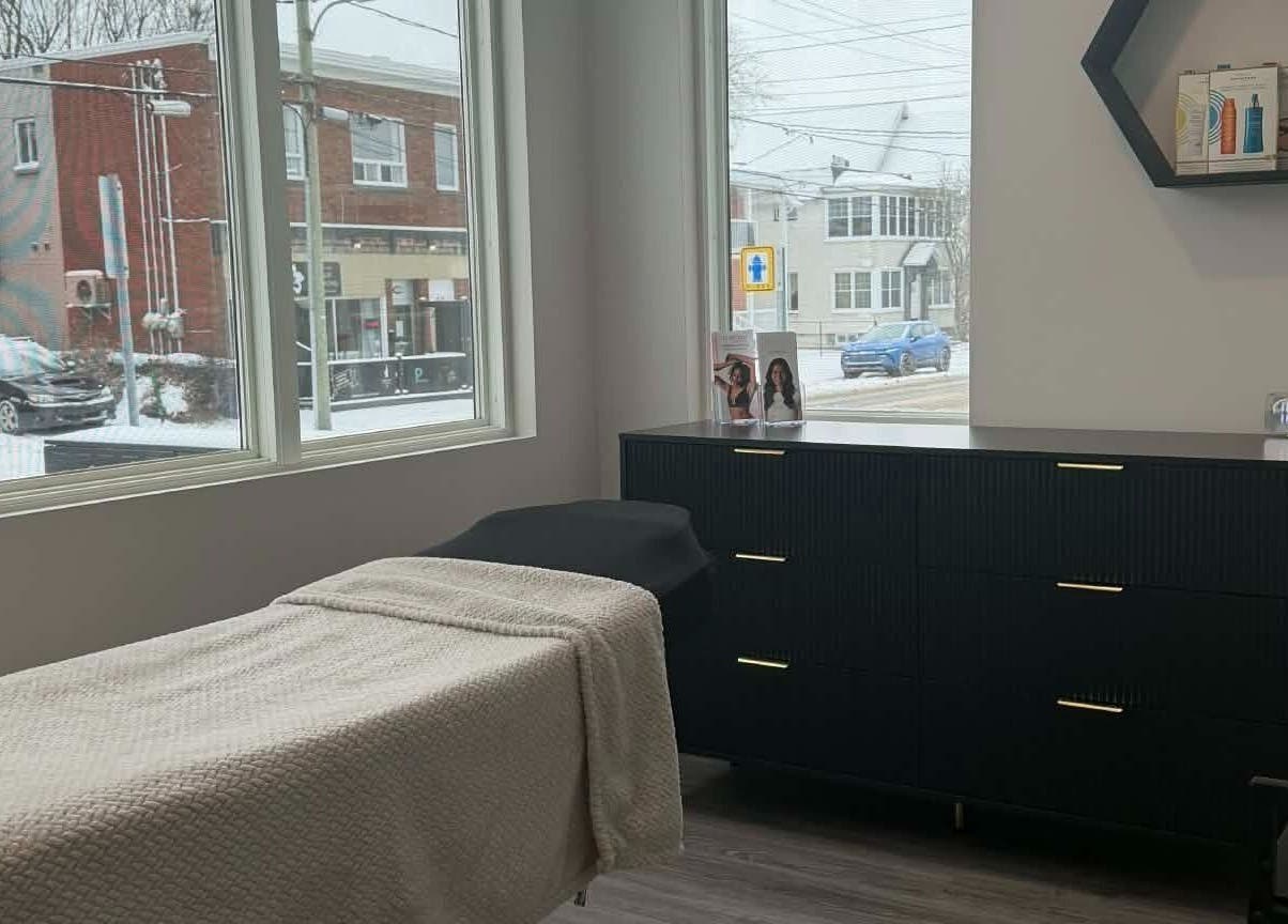 Salle de soin lumineuse chez Naturel Skin, Granby, Québec, CA, avec table confortable et vue extérieure.