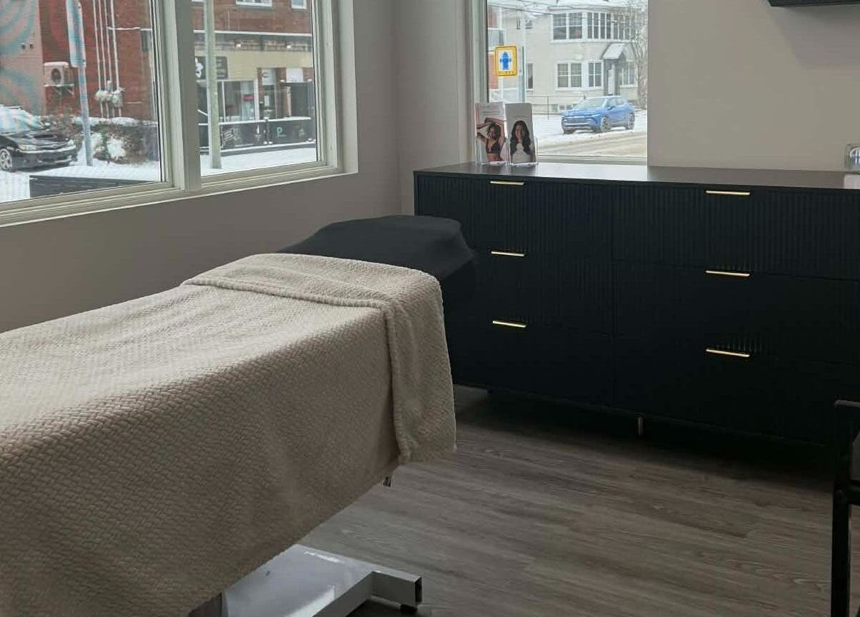 Salle de soin élégante chez Naturel Skin, Granby, Québec, CA, avec table de massage et grande fenêtre.