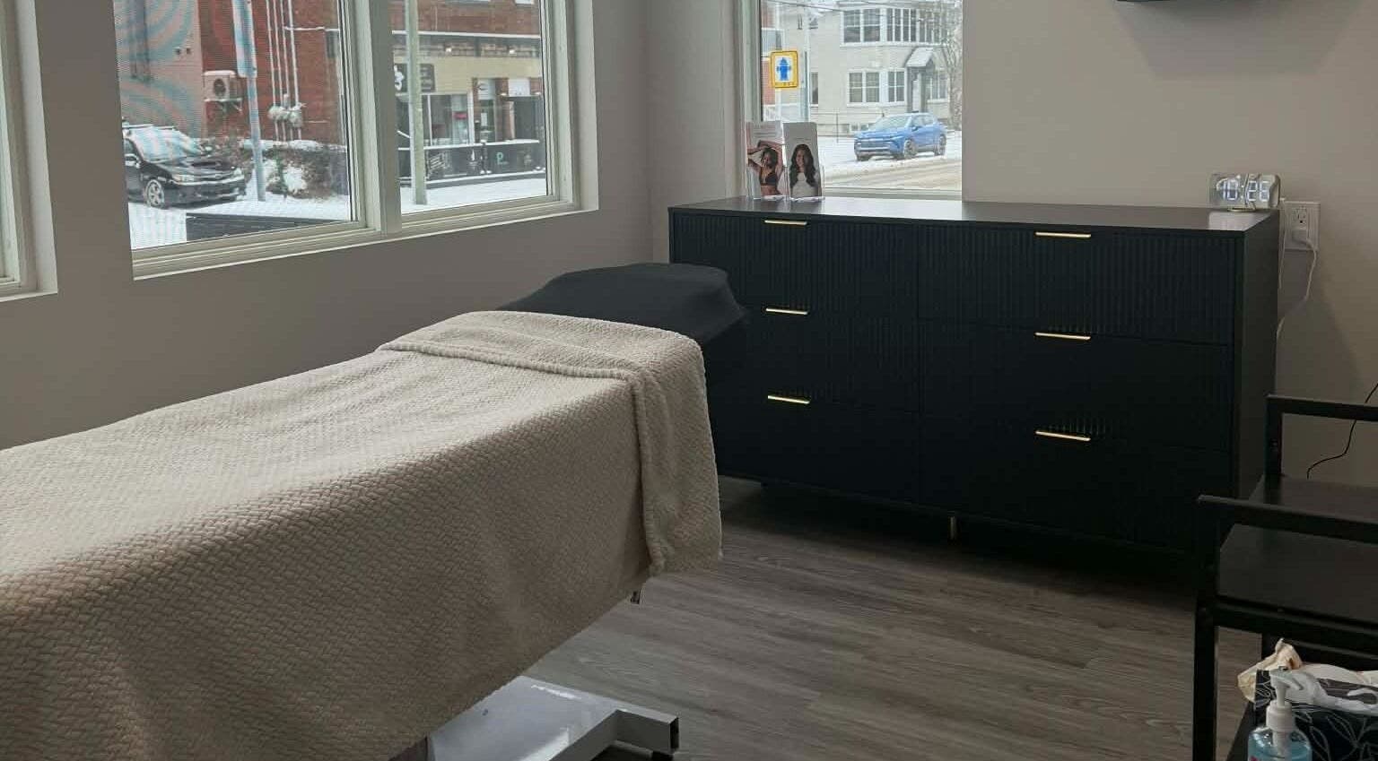Salle de soin élégante chez Naturel Skin, Granby, Québec, CA, avec table de massage et grande fenêtre.