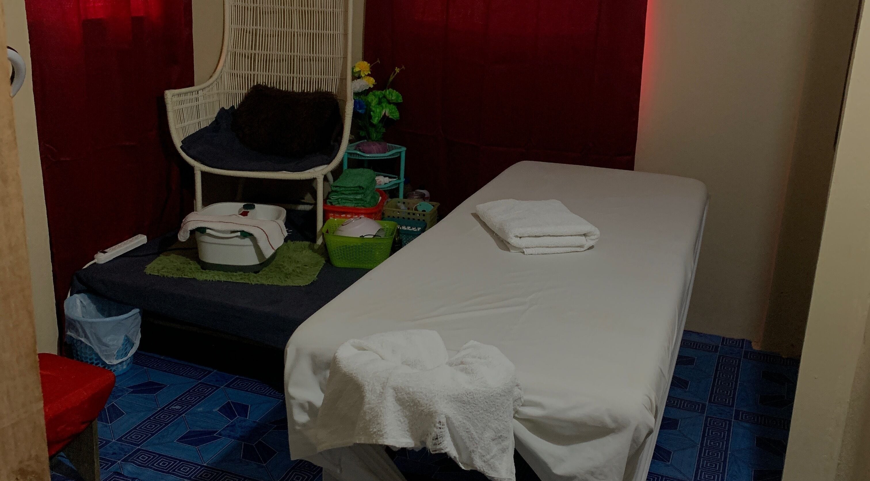 Relaxing treatment room at Glam Harmony Day Spa, Dennery, LC, featuring massage table and cozy chair.