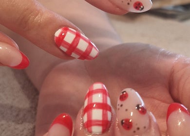 Stylish nail art with red accents at Chloe's, Woodville, England, GB. Featuring ladybugs and checked patterns.