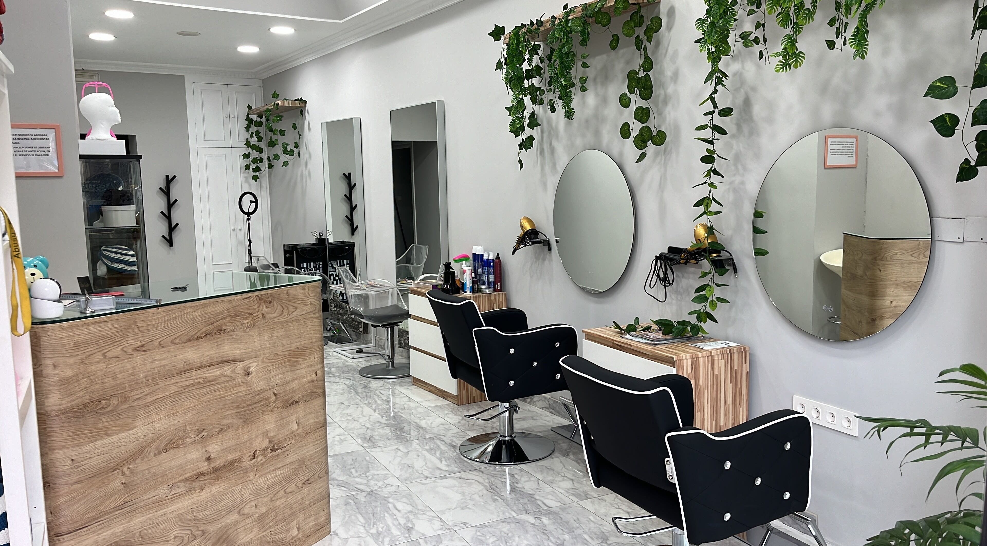 Salón moderno en Elite Hair, Bilbo, Euskadi, ES con espejos redondos y plantas colgantes.