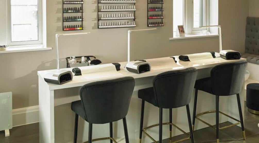 Manicure stations at Hr Treatment Rooms, Huddersfield, GB, featuring elegant seating and nail polish display.