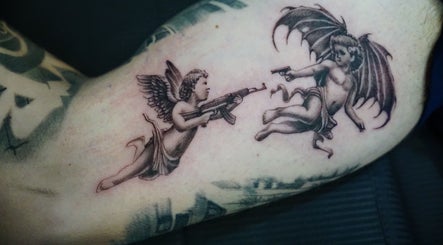 Unique cherub gun tattoo at Z A Tattoo, Bolton, England, GB showcasing artistic detail.