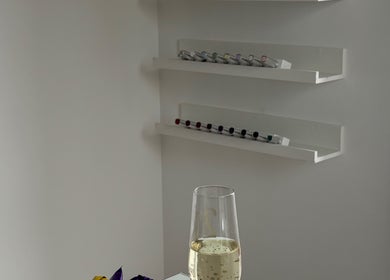 Modern shelving at CLN Cosmetics in Newport, Wales, GB displaying lip products and a glass of sparkling beverage.