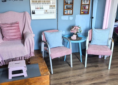 Relax at El Shaddai Beauty Bar, Cape Town, Western Cape, ZA. Inviting seating with pink decor and elegant nail polish display.