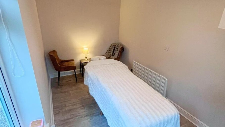 Relaxing therapy room at Woodview Holistic Therapies, Sheffield, England, GB, featuring a massage table and cozy chair.