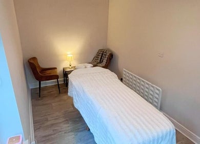 Relaxing therapy room at Woodview Holistic Therapies, Sheffield, England, GB, featuring a massage table and cozy chair.