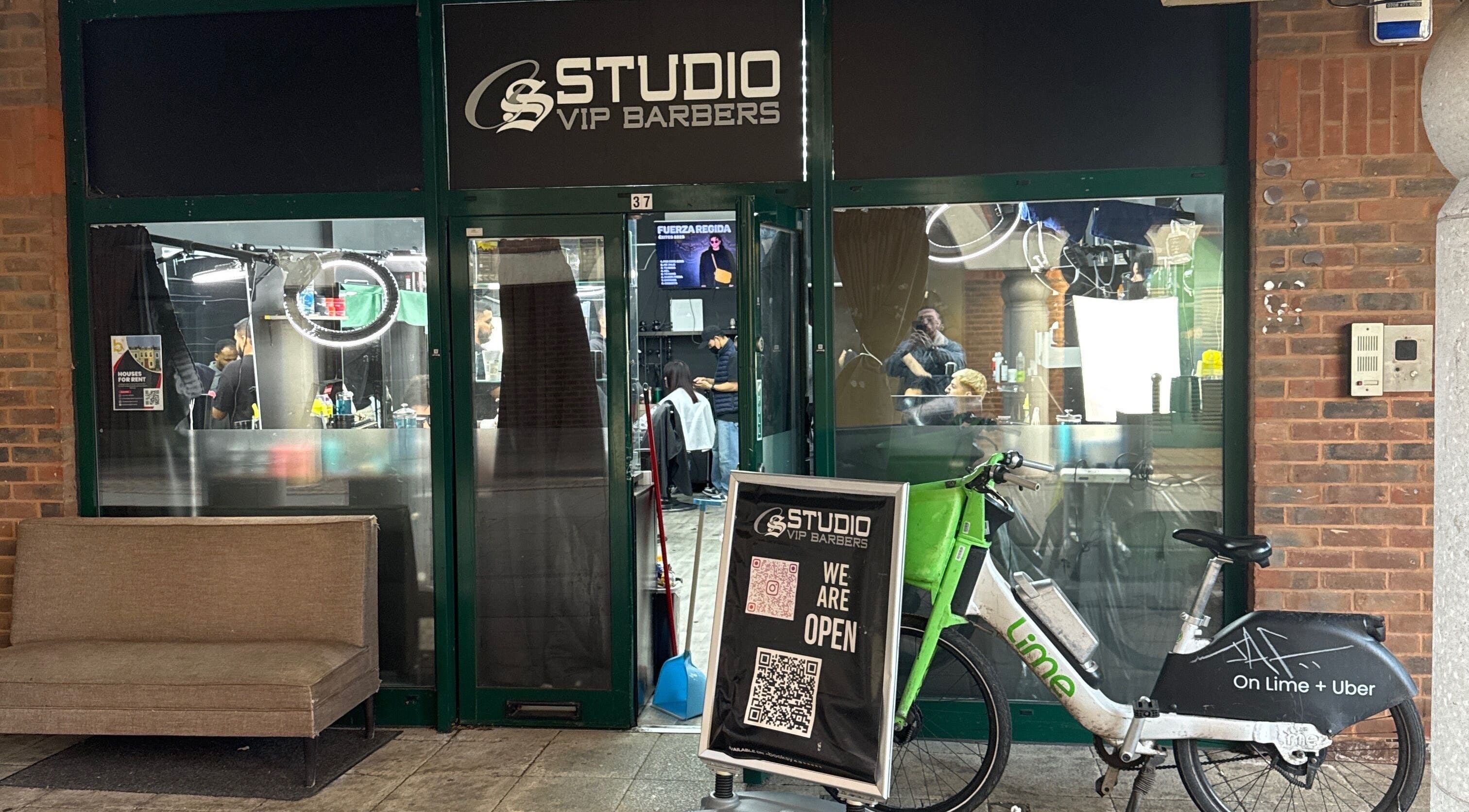 Entrada de White Lion Barber en Londres, Inglaterra, GB, con bicicleta afuera y clientes dentro.