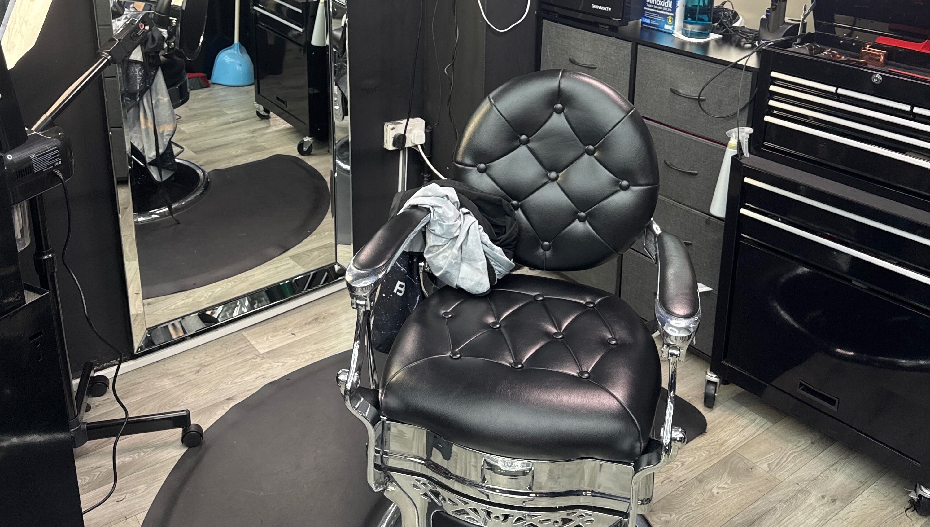 Silla de barbero en White Lion Barber, Londres, Inglaterra, GB, reflejada en un espejo y equipada con herramientas.