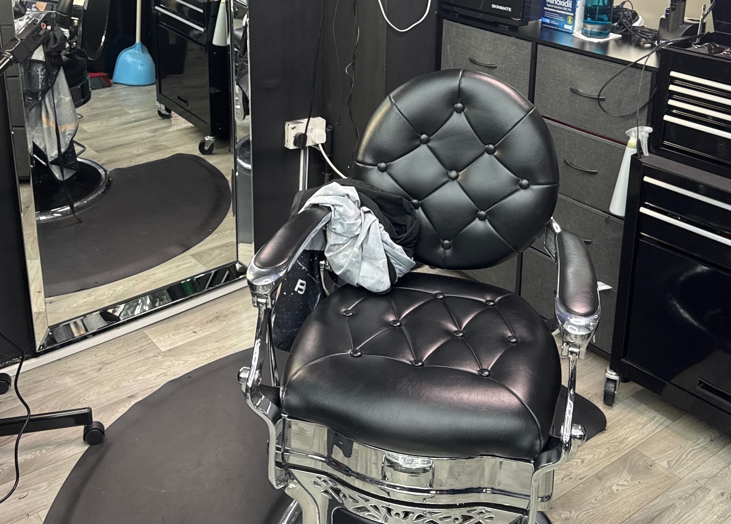 Silla de barbero en White Lion Barber, Londres, Inglaterra, GB, reflejada en un espejo y equipada con herramientas.