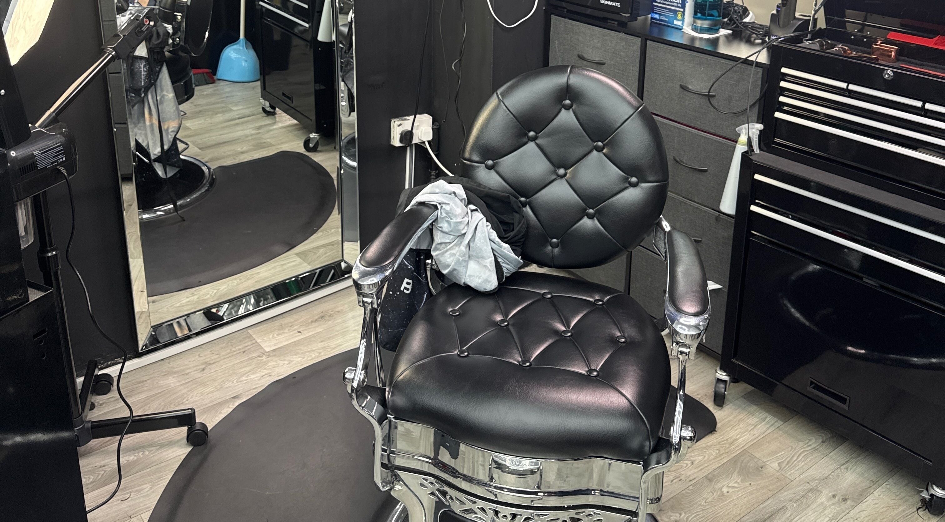 Silla de barbero en White Lion Barber, Londres, Inglaterra, GB, reflejada en un espejo y equipada con herramientas.