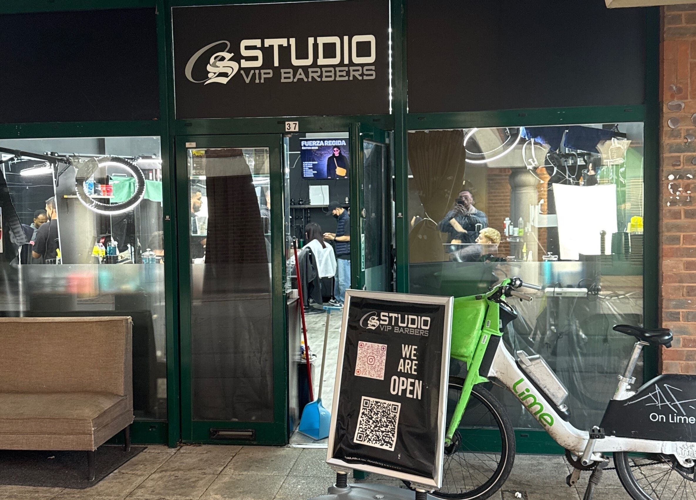 Entrada de White Lion Barber en Londres, Inglaterra, GB con un cartel de bienvenida y bicicleta compartida enfrente.