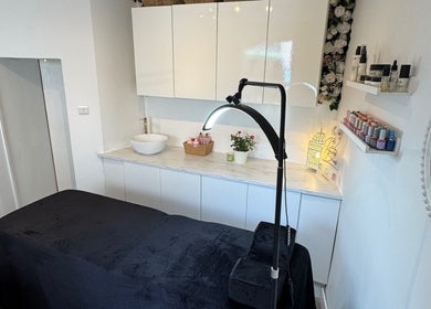 Cozy treatment room at Infinity Brows, Poole, England, GB with soft lighting and beauty products on display.