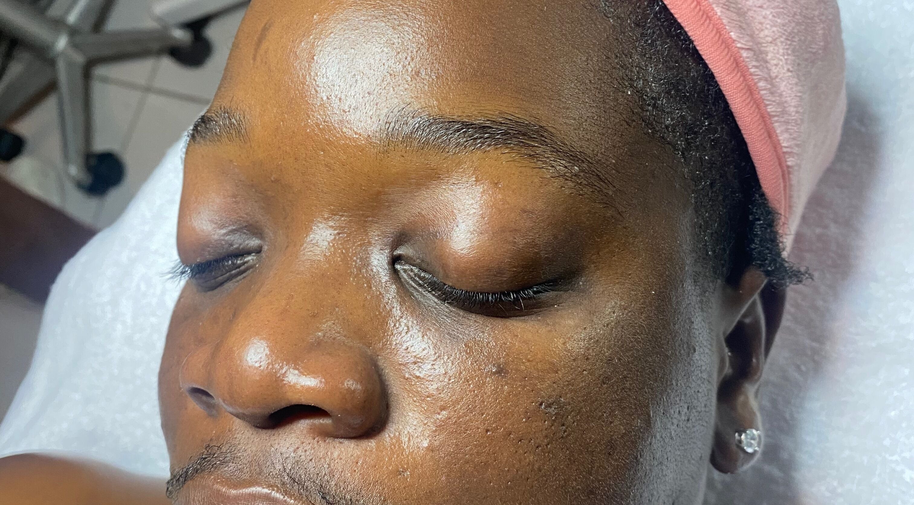 Close-up of a relaxed person at SkinDeep in Nassau, New Providence, BS, receiving a facial treatment.